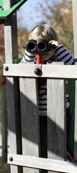 Ein Kind schaut durch ein Fernrohr, das an einem Kletterturm auf dem U3-Spielplatz angebracht ist.