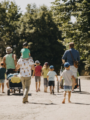 Familiengruppe geht mit Bollerwagen spazieren.
