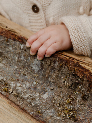 Kinderhand hält ein Stück Holz.